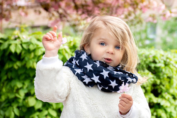 blue-eyed little blond girl on a background of nature in a scarf with stars