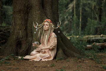 Charming girl in the image of a fairy in the forest thicket
