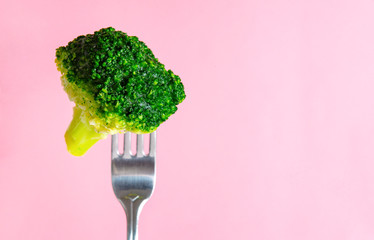 fresh green broccoli on a fork on a pink background