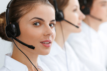 Call center. Beautiful young woman using headset and computer to help customers. Business concept