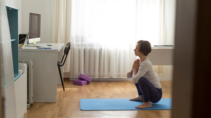 Woman doing yoga at home online video.