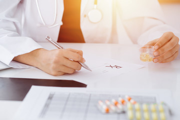 Unknown woman-doctor fills up prescription form in sunny room, close-up
