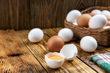 Farm eggs white and brown lie on a wooden table and in a basket, close-up, low light, selective focus, shallow depth of field. Organic food concept