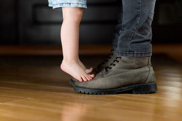 child meets or escorts his father to work. A girl stands on her father's boots