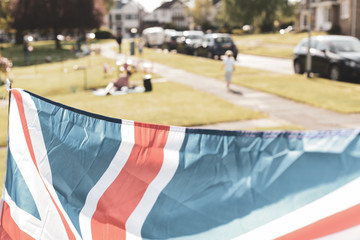 Vitage style Union Jack flag flying in front of VE Day celebrations at a social distance street party in May 2020