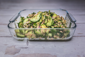 Tuna and Avocado Salad with Cucumber, Red Onion, Lemon juice, Cilantro, Black Pepper, Olive oil, and salt. Salad on the wooden retro / vintage table.