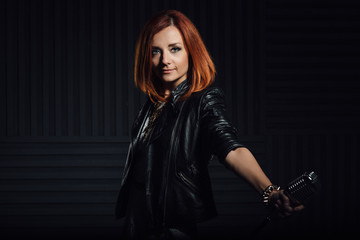 young red-haired girl in a white dress and a black leather rocker jacket sings into the microphone