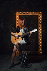 Fototapeta na wymiar young girl with red hair with an acoustic guitar