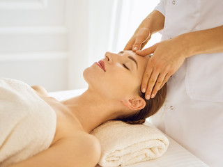 Fototapeta na wymiar Beautiful woman enjoying facial massage with closed eyes