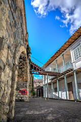 Old house in front of the ancient and famous stone Puente Roto, or Broken Bridge, on a sunny afternoon, Cuenca, Ecuador.