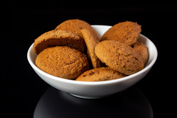 Appetizing oatmeal cookies in a white plate close-up on a black mirror background. Horizontal orientation. 