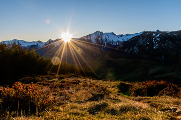 A picturesque landscape view of the hiking trail in the field in front of the snow capped French Pyrenees mountain range early in the morning during the sunrise (Col de Soum)