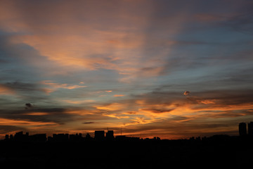 Warm and colourful sunset with city landscape and tall buildings in the foreground