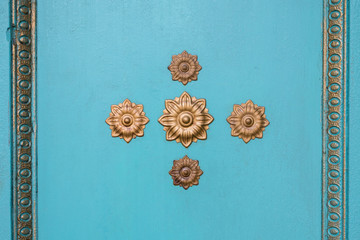 Turquoise wall with ornaments flowers in gold. Texture.