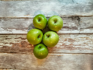 Five green apples on background with aged wooden boards