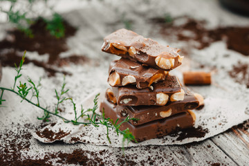 Hazelnut and almond milk chocolate pieces tower is recycled paper on wooden table