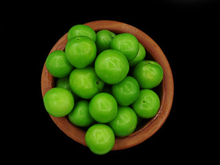 Green plums in a pottery bowl                               