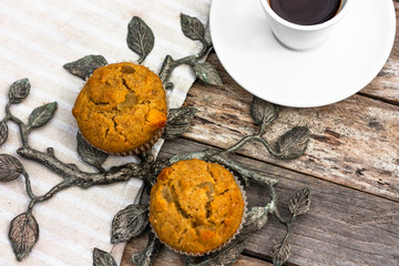 Fototapeta premium Fresh banana muffins and cup of coffee espresso on wooden table with wrought iron elements. Top view. Morning breakfast concept