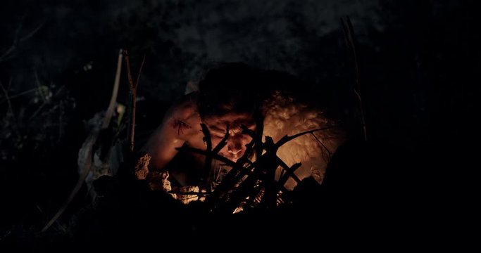 Bearded barbarian making fire at night