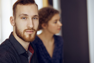 Red-bearded friendly adult businessman looking at camera. Business headshot or portrait in sunny office