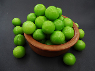 Green plums in a pottery bowl                               