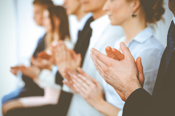 Fototapeta na wymiar Business people clapping and applause at meeting or conference, close-up of hands. Group of unknown businessmen and women in modern white office. Success teamwork or corporate coaching concept
