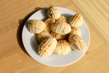 Traditional eastern mamoul cookies with nuts. Arabic baked sweets on white plate on light wooden table. Mamoul Eid for Islamic feast. 