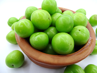 Green plums in a pottery bowl                               