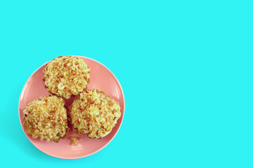 three cakes with peanuts lie on a pink plate on a blue background
