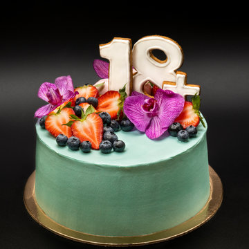 Turquoise fruit cake with numbers 18plus with strawberries, blueberries and orchid flowers.