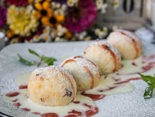 cheese pancakes with syrup on plate close up with flowers on background