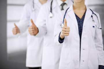 Doctors standing as a team with thumbs up in clinic and ready to help patients. Medical help, insurance and medicine concept