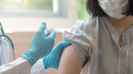 World immunization week and International HPV awareness day concept. Woman having vaccination for influenza or flu shot or HPV prevention with syringe by nurse or medical officer. - obrazy, fototapety, plakaty