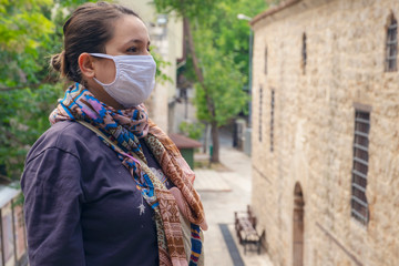 Obraz premium Young adult woman standing look at the camera with mask during corona (covid19) outbreak in the street. 