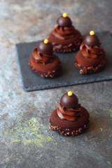Contemporary chocolate mini mousse cakes with matcha green tea cream insert and mango jam, covered with chocolate velvet spray and chocolate gourmet glaze, decorated with whipped chocolate ganache, on