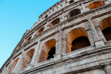 colosseum in rome italy, backlit against a blue sky on the sunset