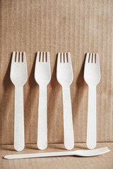 Wooden forks on a cardboard background. Eco friendly disposable tableware. Copy, empty space for text