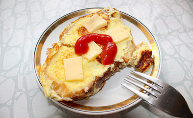 On a plate of fried toast with eggs, cheese and ketchup.