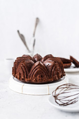Homemade Chocolate bundt cake with melted chocolate on white background.Close up view, selective focus