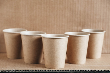 Disposable paper cups on kraft paper background. Eco friendly disposable tableware. Zero waste concept. Copy, empty space for text