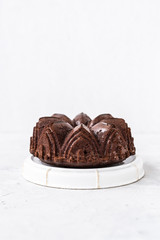 Homemade Chocolate bundt cake with melted chocolate on white background.Close up view, selective focus