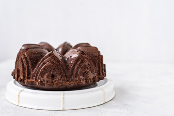 Homemade Chocolate bundt cake with melted chocolate on white background.Close up view, selective focus
