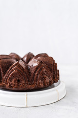 Homemade Chocolate bundt cake with melted chocolate on white background.Close up view, selective focus