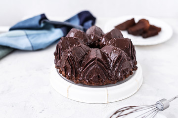 Homemade Chocolate bundt cake with melted chocolate on white background.Close up view, selective focus