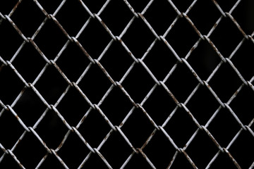 Old rust chain link fence metal wire mesh panel. Black background.