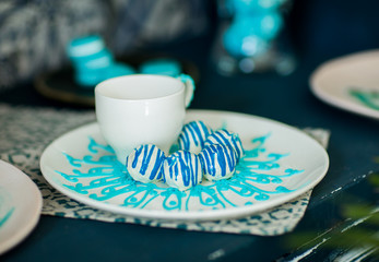 Small blue cookies on a white plate with white cup