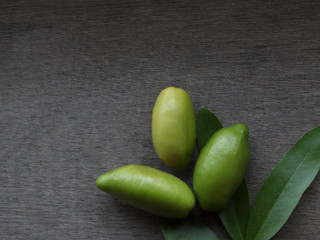 Three Madan fruits and leaves top view  on a wood grain floor.