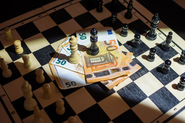 Top view of chessboard with arranged pieces, money with kings on top, agreement concept