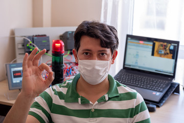 Young Man with surgical mask on face against COVID-19 ( Coronavirusis ) Working at Office and...