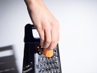 Orange carrots rubs with a blue handle on a white background.